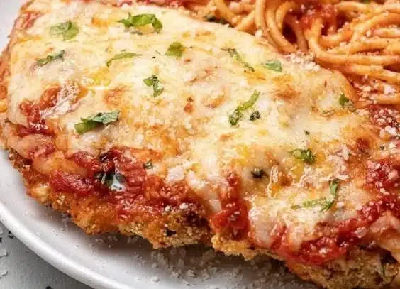 Delicious baked chicken parmesan garnished with fresh herbs and cheese
