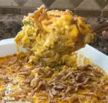 Cheesy chicken broccoli casserole served in a baking dish with melted cheese on top.