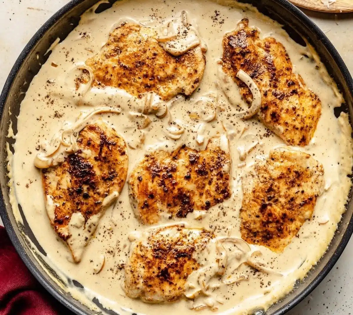 Creamy caramelized onion chicken served on a plate with pasta and vegetables
