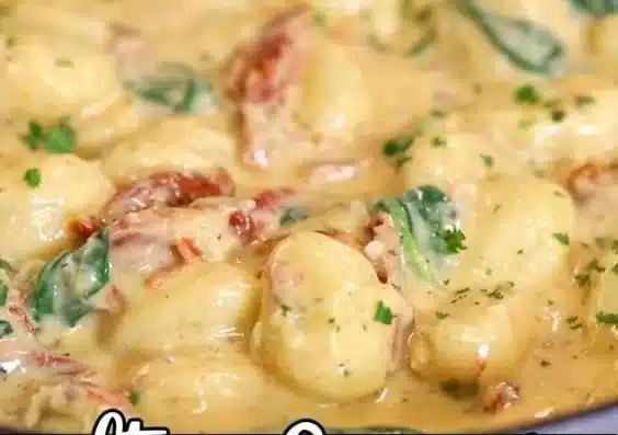 Creamy Tuscan gnocchi dish garnished with fresh herbs.