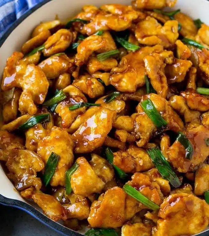 Delicious Mongolian Chicken stir fry on a plate with vegetables and rice